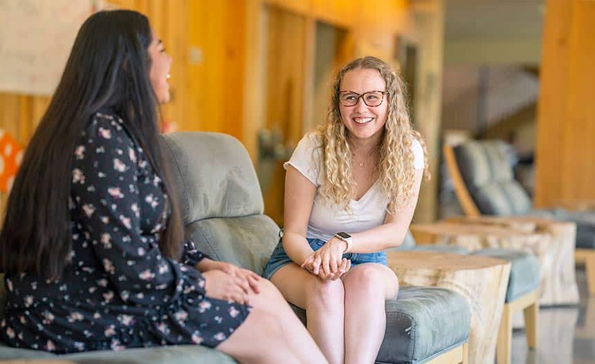 two female students looking at each other and laughing