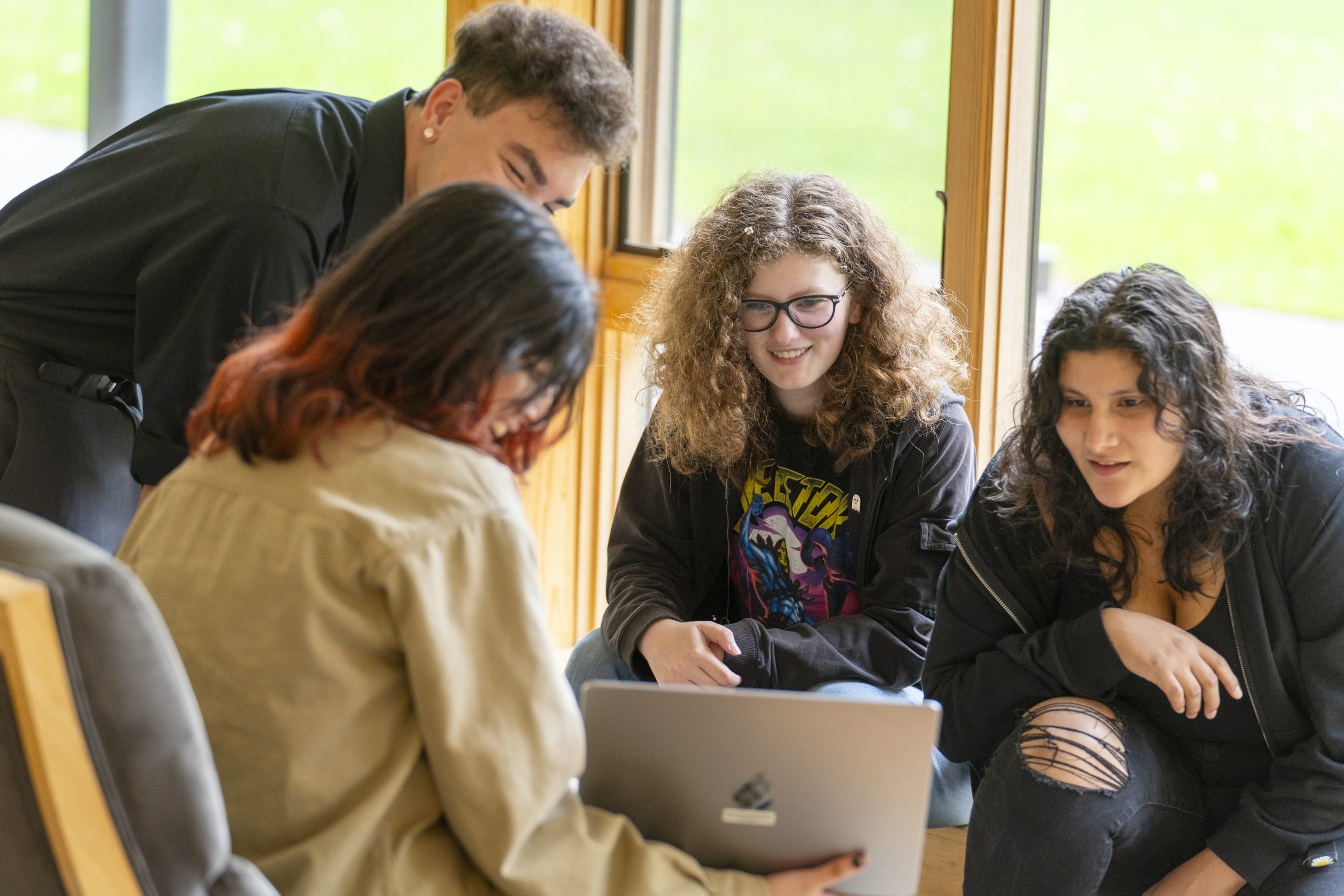 Decorative: Students sitting around a laptop. 